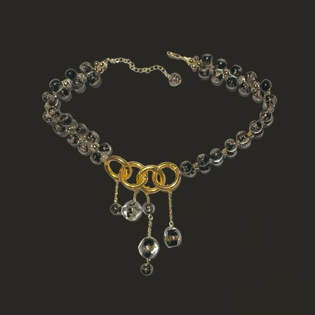 Flat lay of dark gold-flecked glass bead chunky ring cascade choker necklace