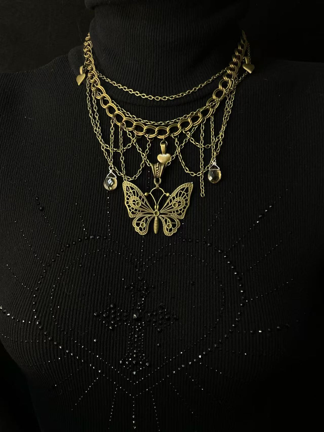 Close-up of filigree bronze butterfly pendant with multi-tiered draped chains and crystals