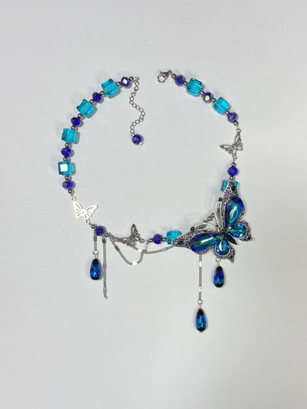 Flat lay of royal blue crystal butterfly asymmetric statement choker on white backdrop