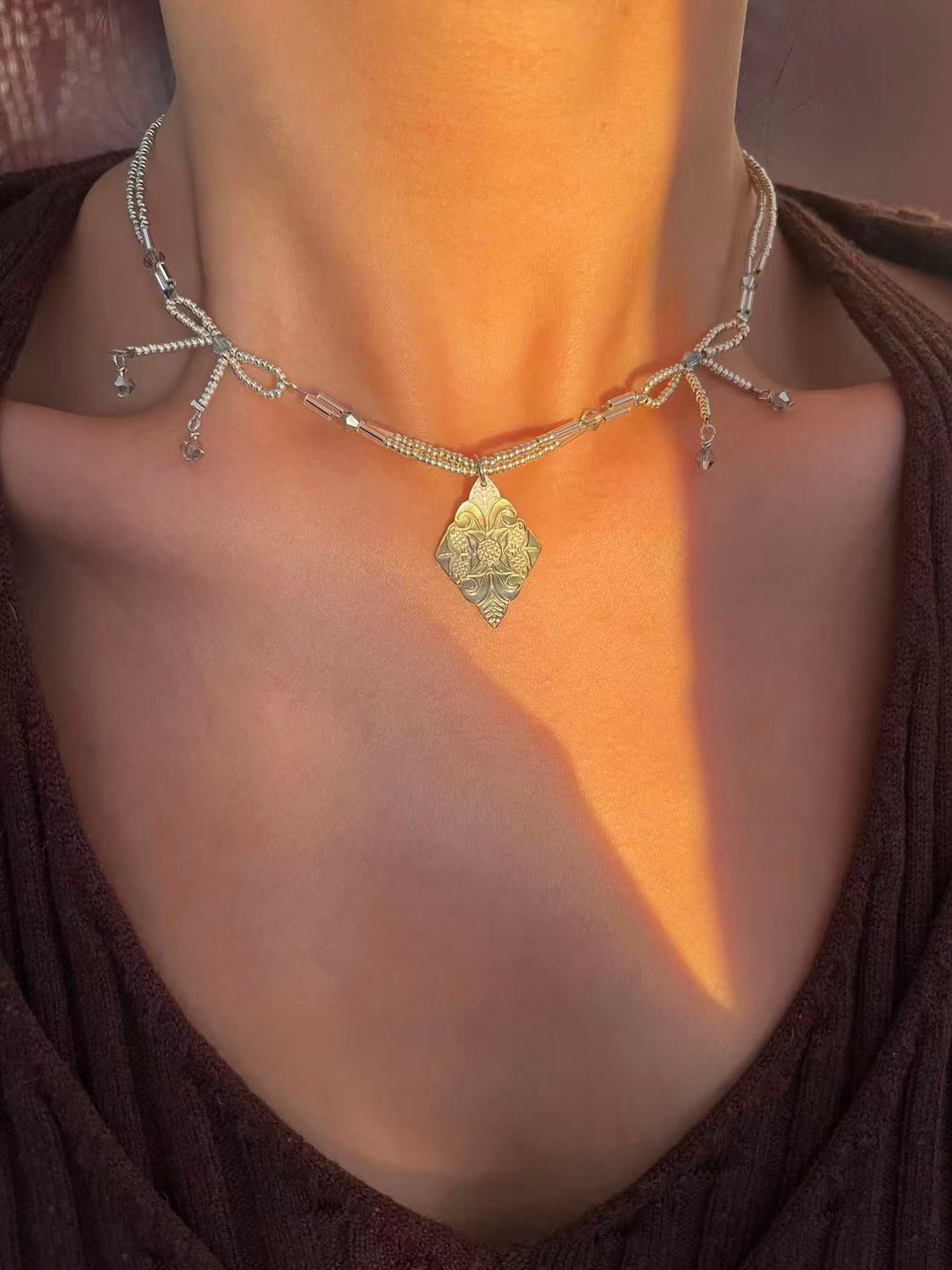Minimalist silver beaded bow choker with engraved diamond pendant on brown V-neck top