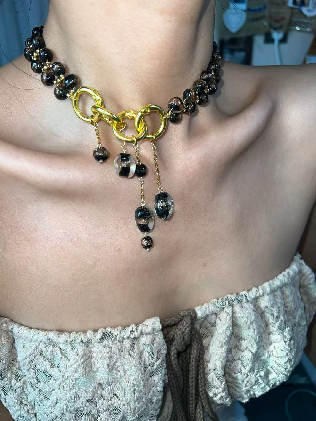 Close-up of chunky gold-plated interlocked rings with cascading glass bead drops