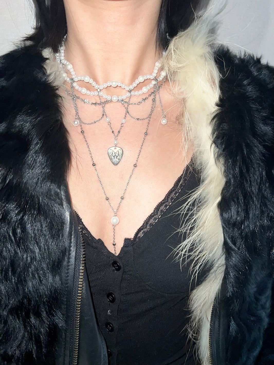 Close-up of engraved butterfly guitar pick pendant with draping silver chain and pearl Y-lariat