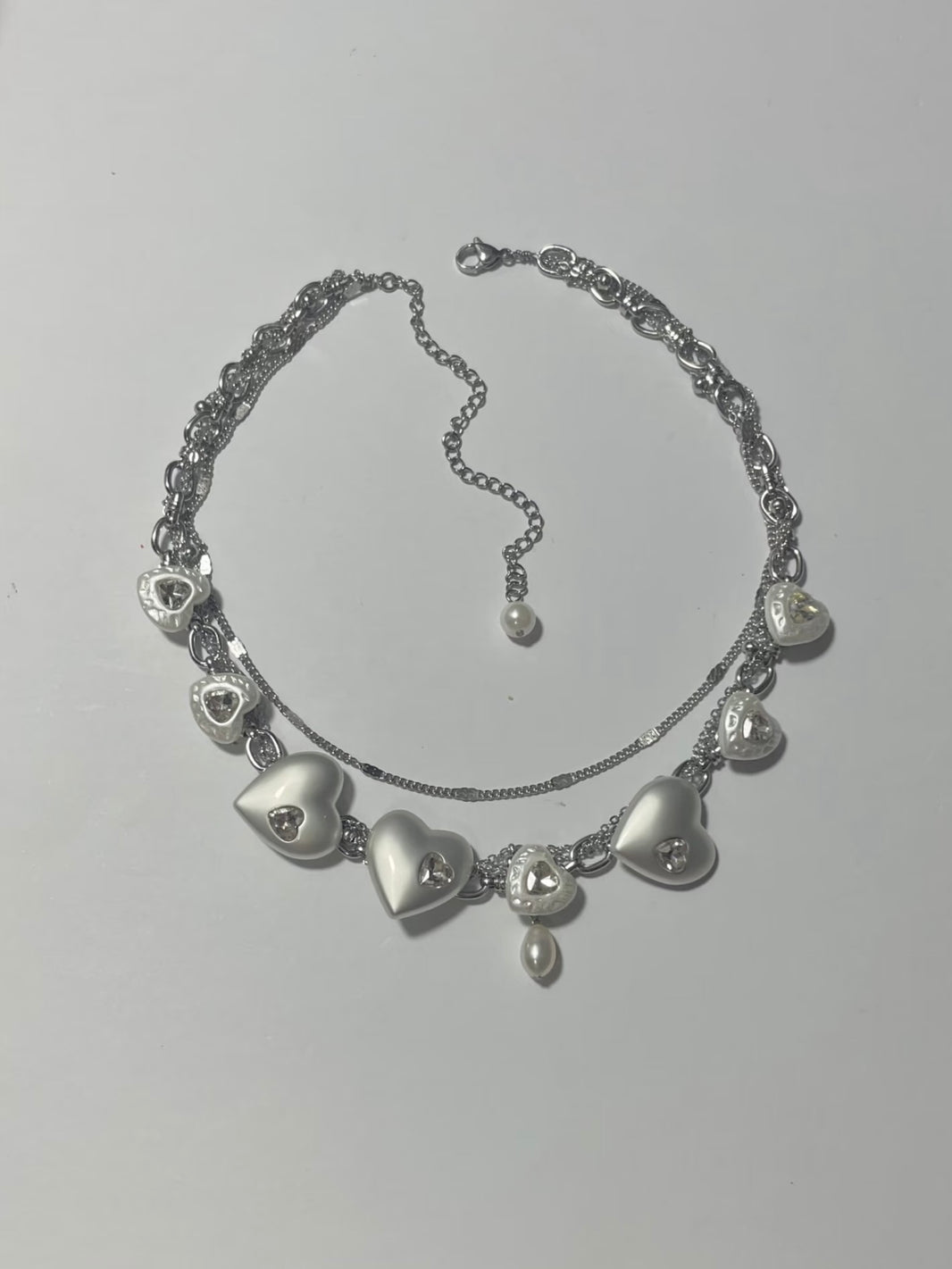 Flat lay of convertible Y2K matte heart choker necklace and multi-wrap bracelet
