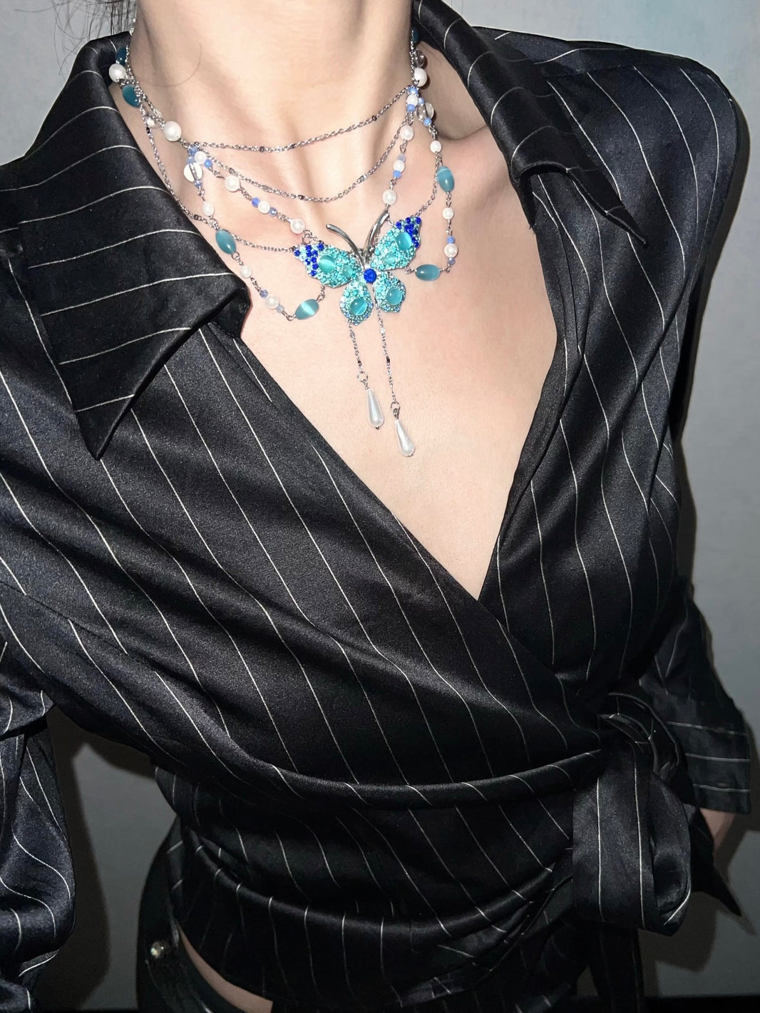 Jewel paved blue butterfly cat's eye pearl layered necklace styled on model
