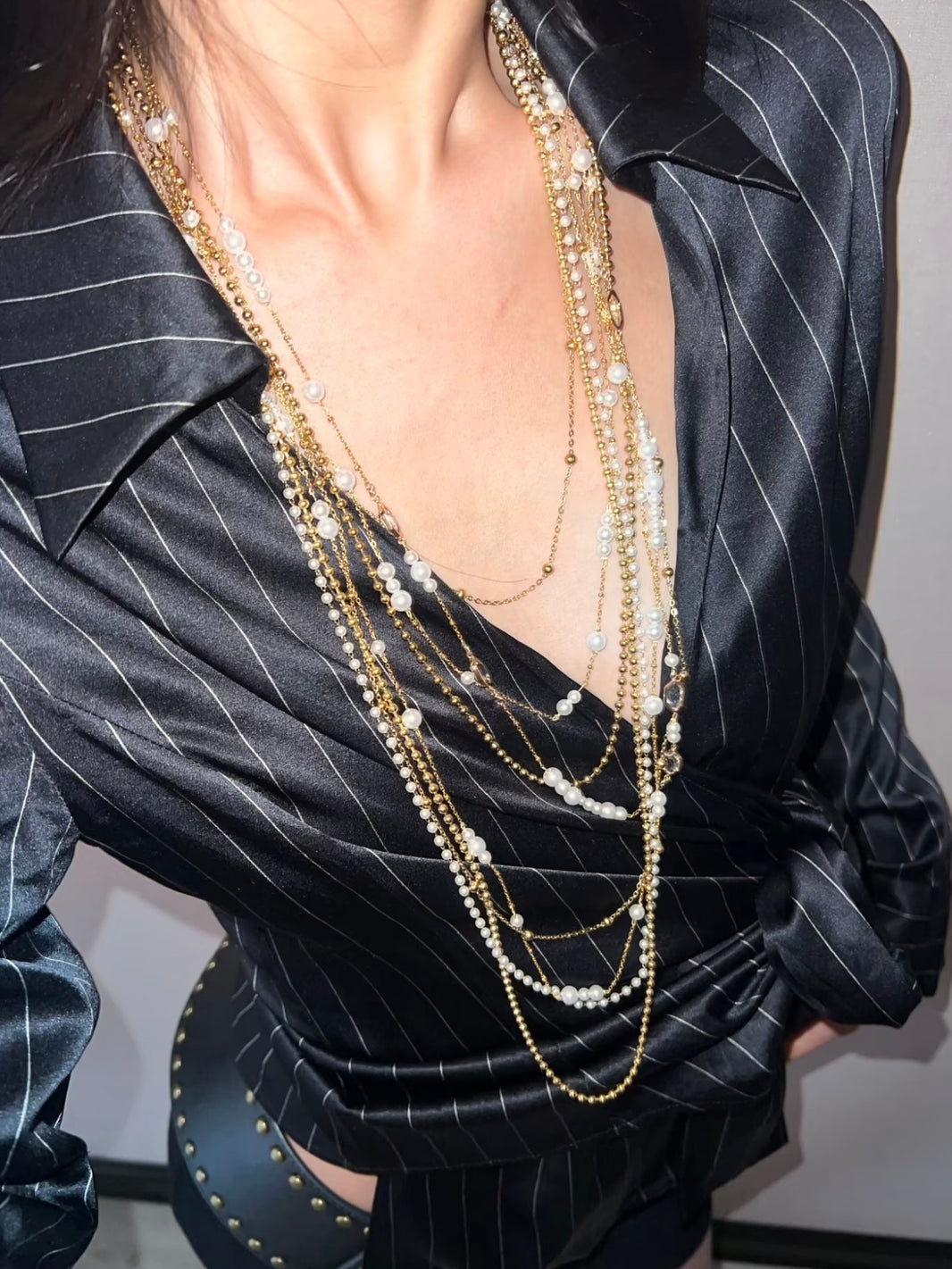 Multi layered gold chain and pearl strand necklace styled with a pinstripe shirt