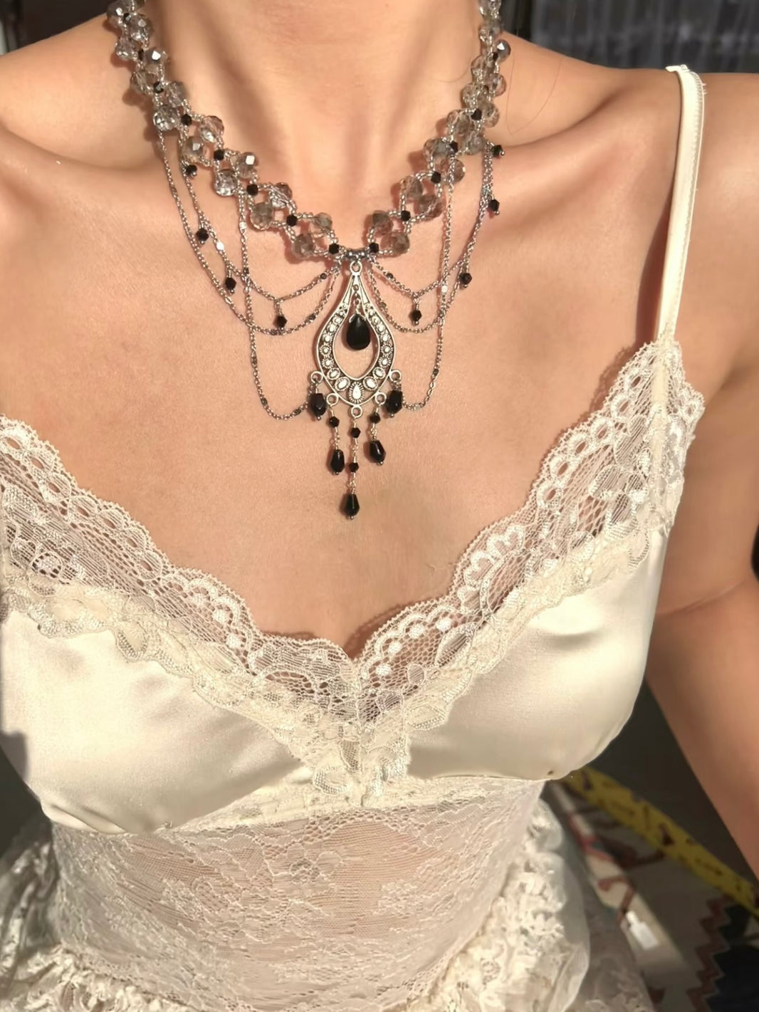 Close-up of silver filigree teardrop pendant with dangling black crystal beads