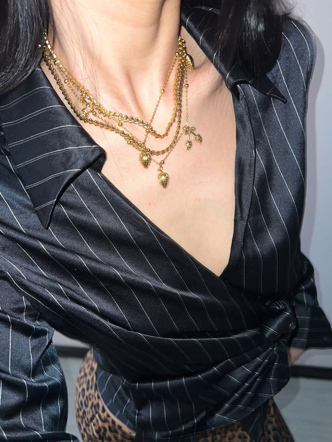 Close-up of gold strawberry pendant layered chain necklace for romantic date night look