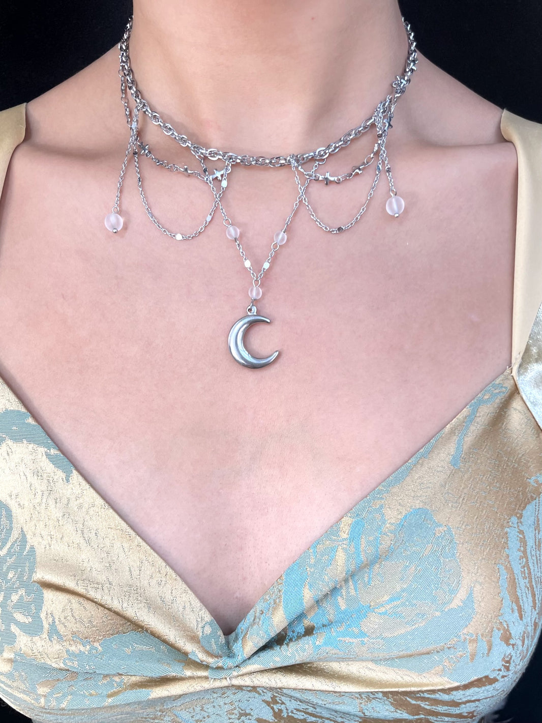 Close-up of polished silver crescent moon pendant with draping chain fringe and crystal beads